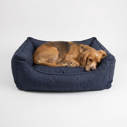 Dog curled up resting in the navy denim bolster dog bed