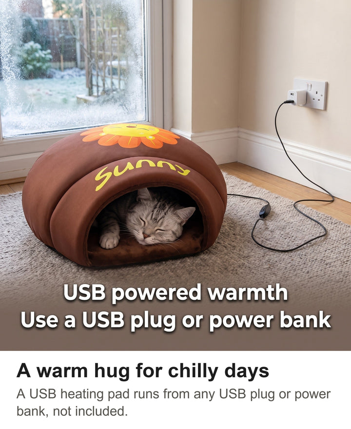 Silver tabby cat asleep in a brown heated cat cave bed plugged into a USB wall plug