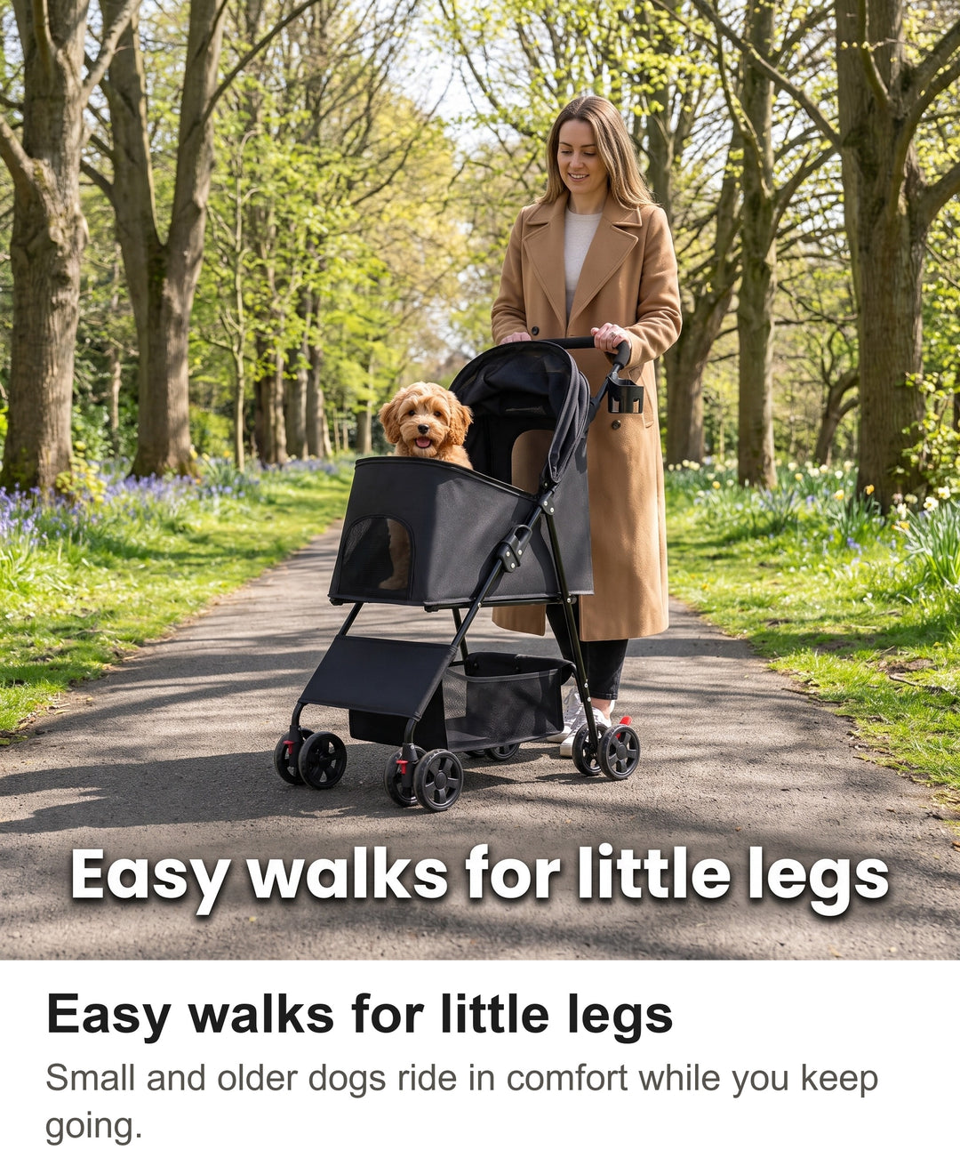 Woman pushing a small dog in the black folding dog pram through a park