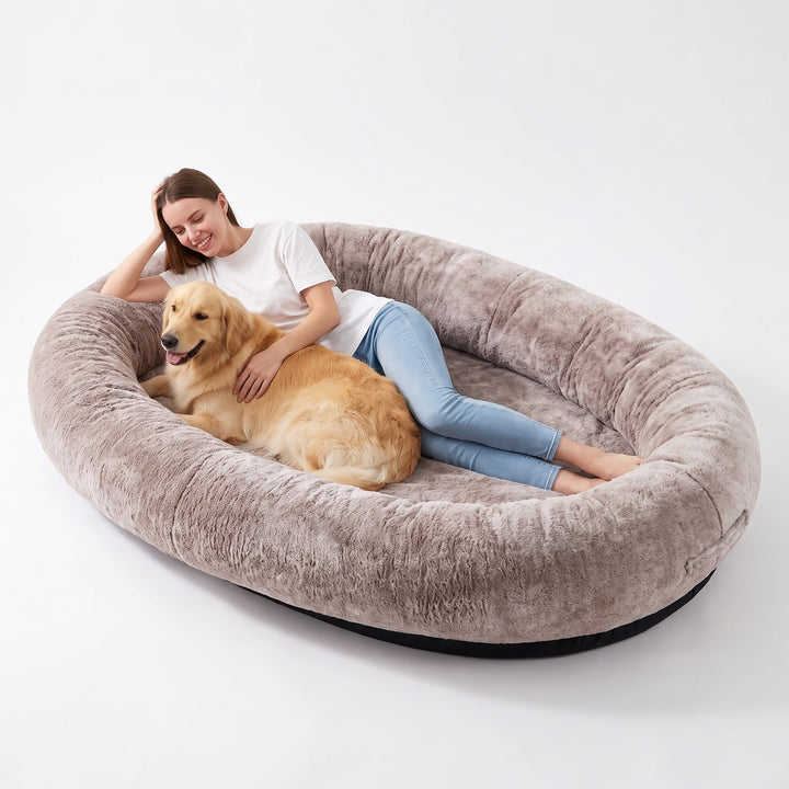 Woman and golden retriever lying together in the giant khaki human dog bed