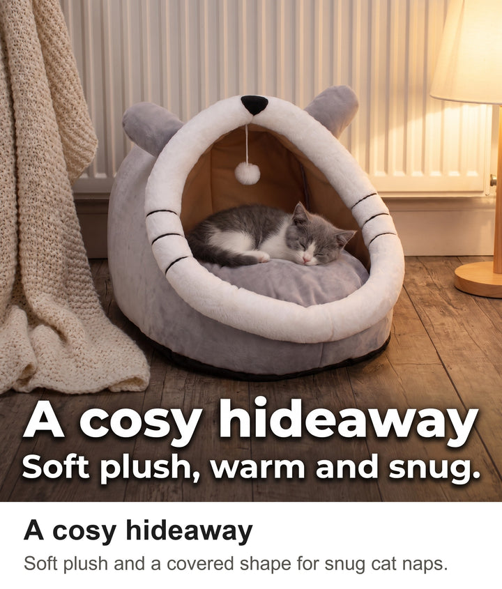 Grey and white kitten asleep inside the cat cave bed by a radiator