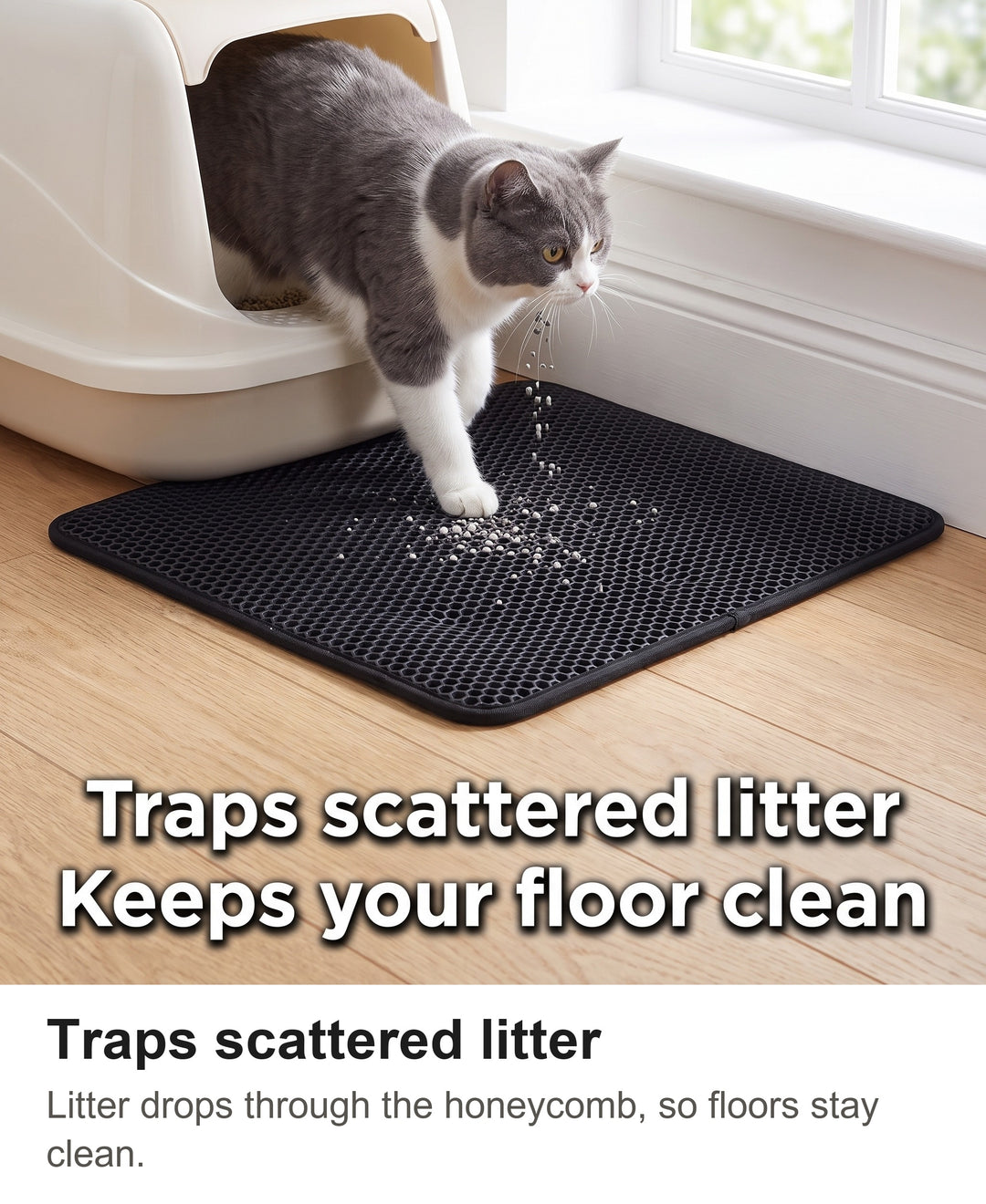 Grey and white cat stepping out of a litter box onto the black cat litter mat as litter falls into the honeycomb