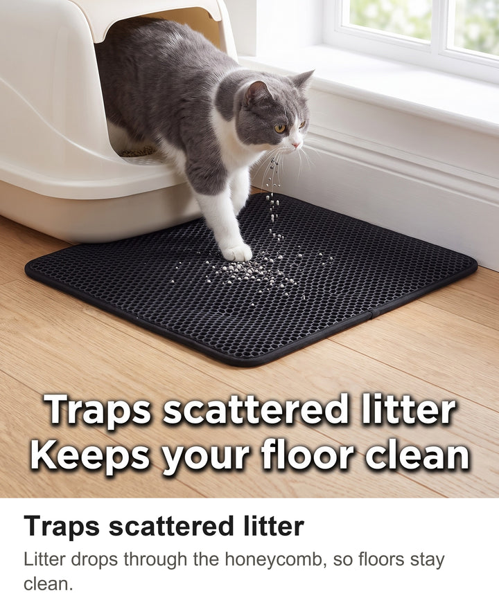 Grey and white cat stepping out of a litter box onto the black cat litter mat as litter falls into the honeycomb