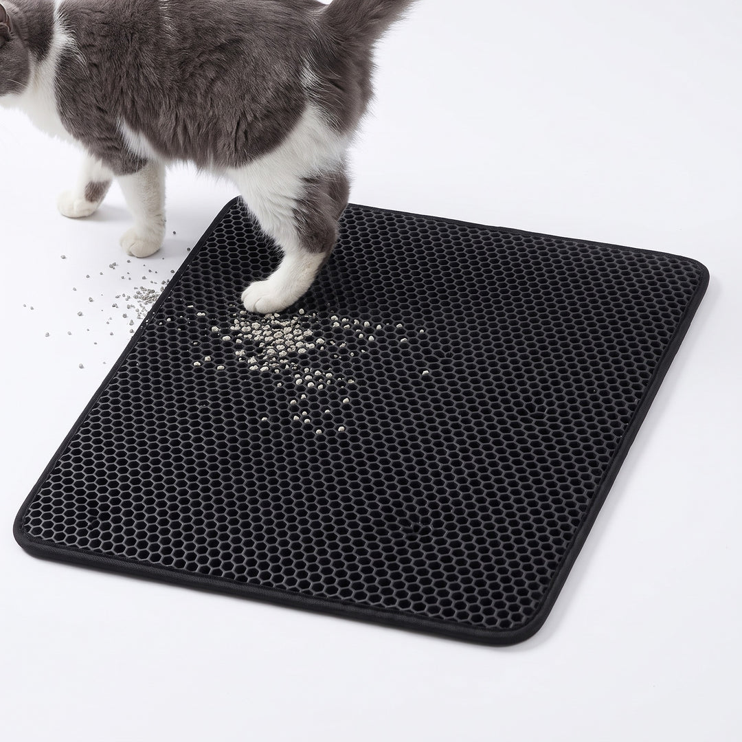 Black double layer cat litter mat with a grey and white cat stepping off it
