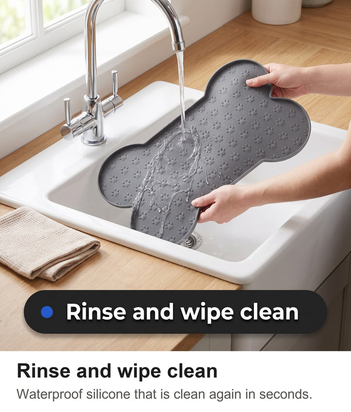 Hands rinsing the grey silicone feeding mat under a kitchen tap