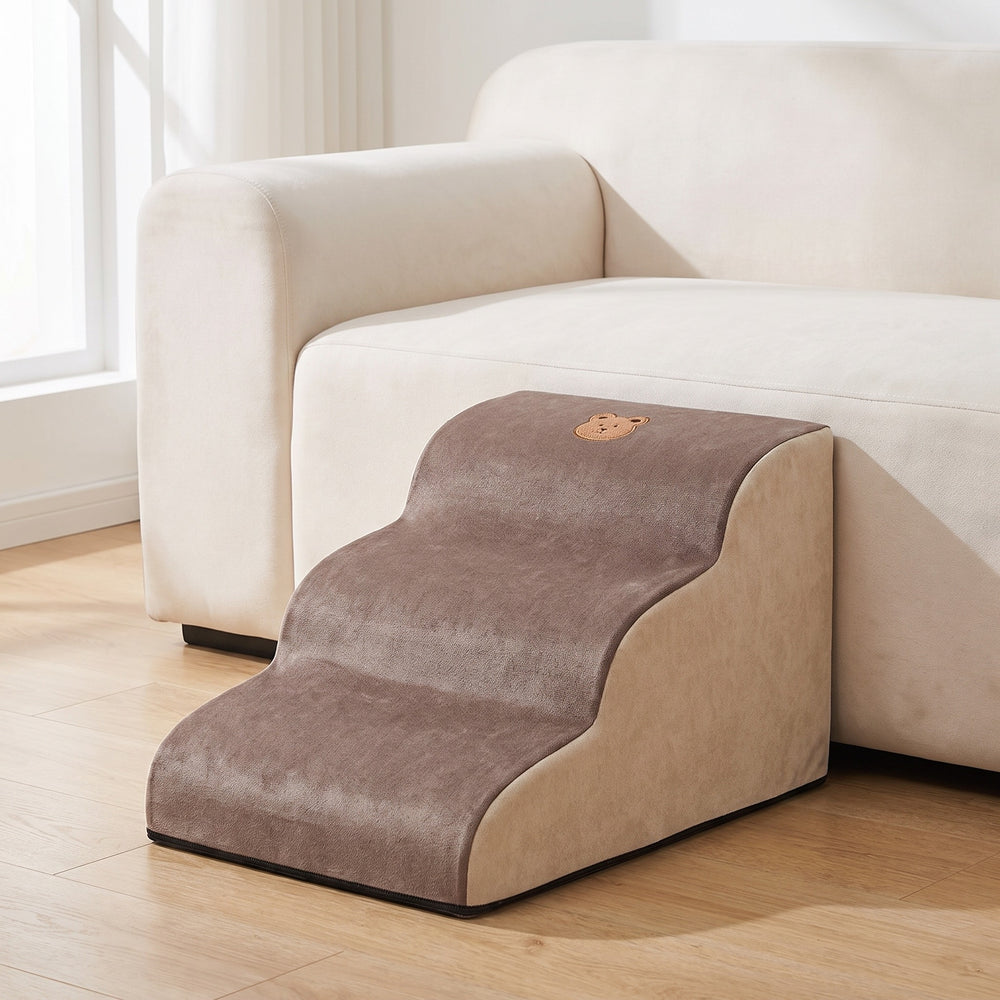 Brown and cream foam dog steps with 3 steps beside a light sofa in a bright living room