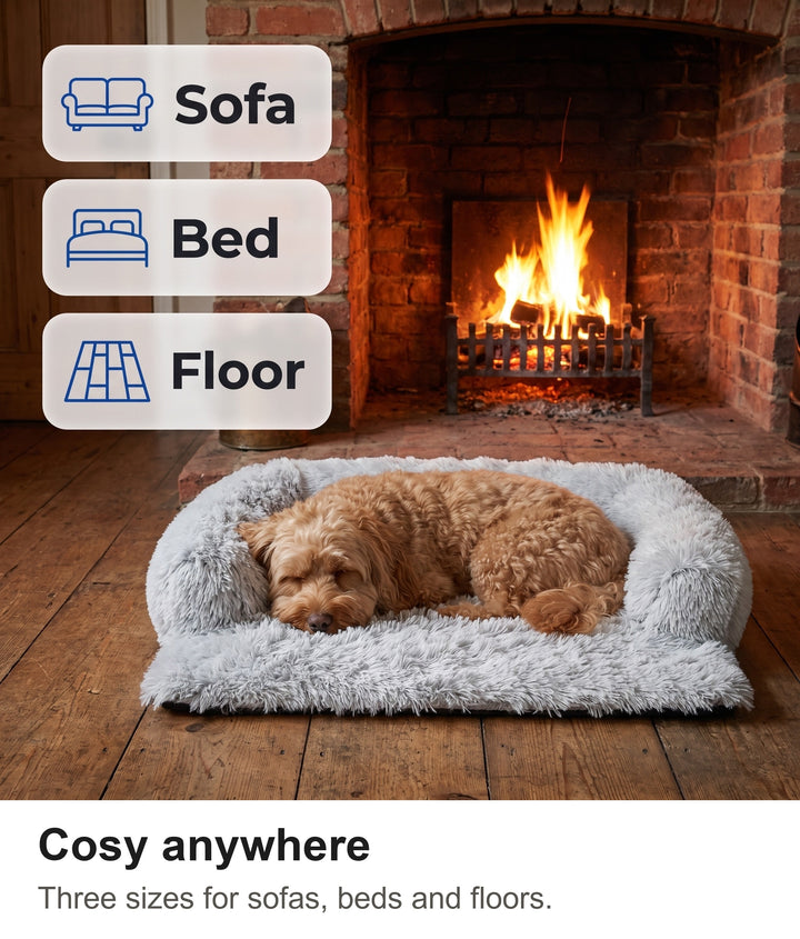 Dog asleep in the fluffy dog couch cover on the floor by a fireplace