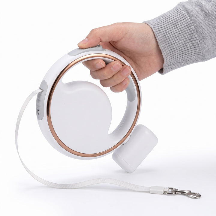 Hand holding the white retractable dog lead with LED light, round handle and poo bag holder