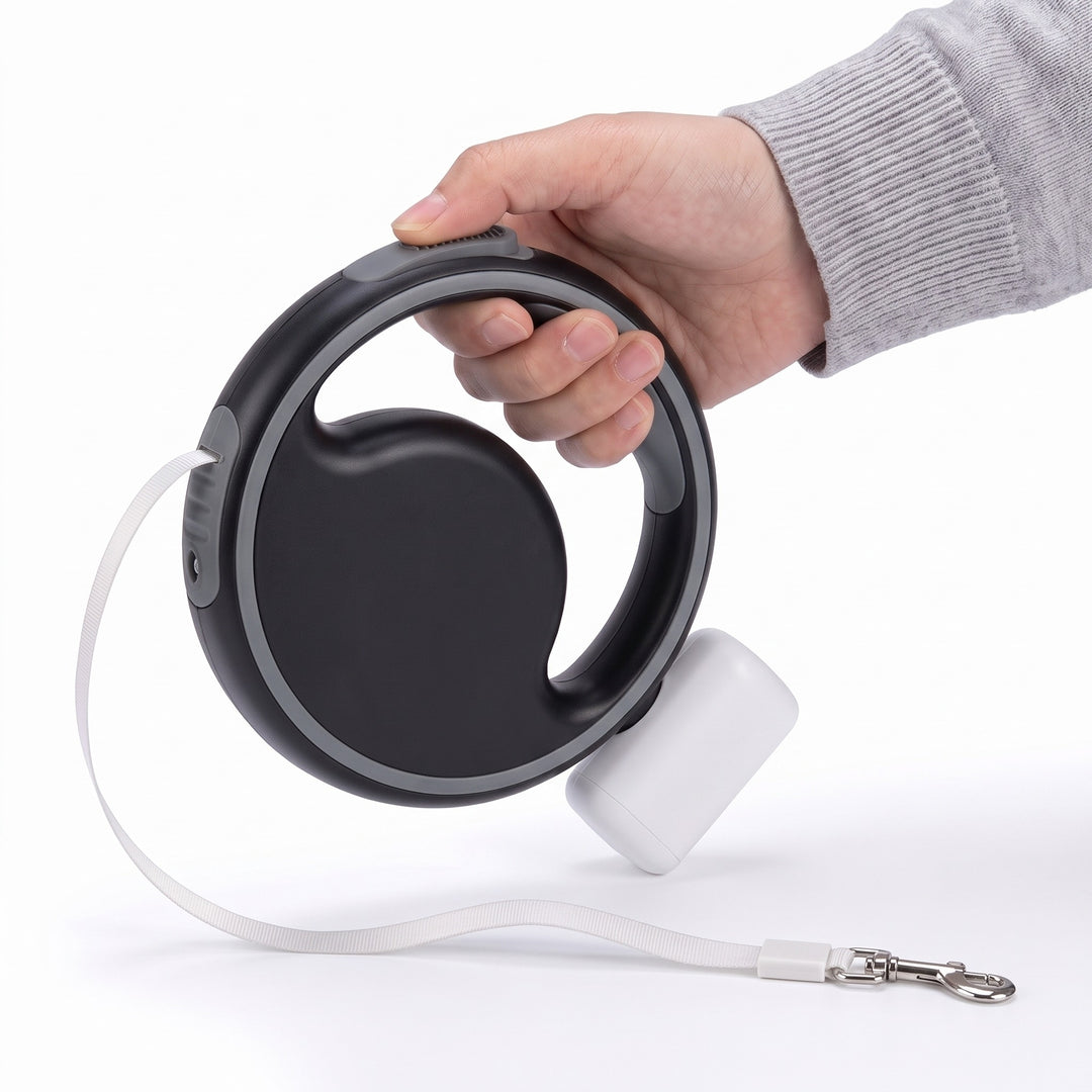 Hand holding the black retractable dog lead with LED light and round handle