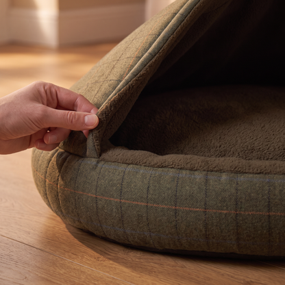 b2 cosy materials: fingers folding the hood edge back so the tweed-style outer and the brushed fleece lining are both vi
